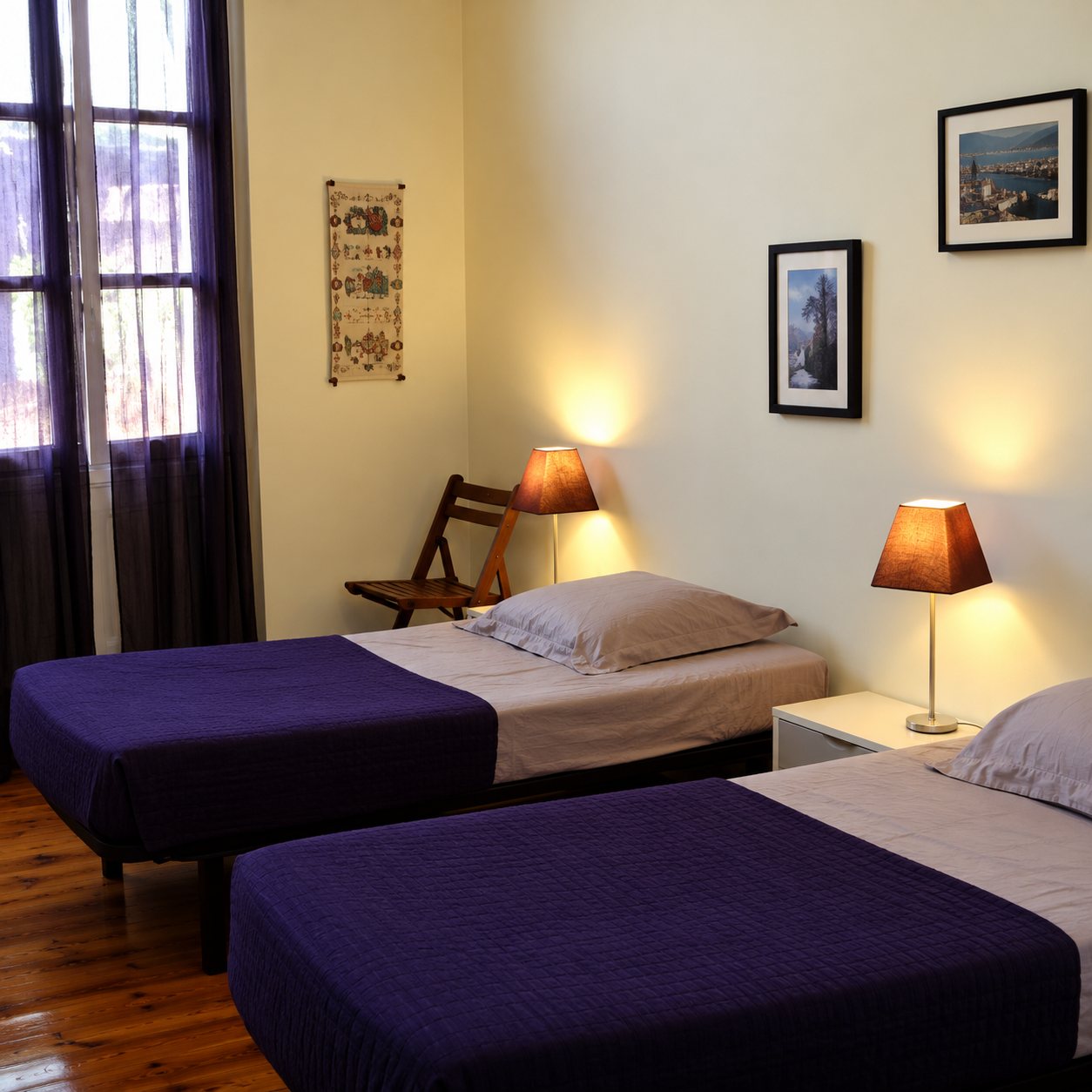 Une chambre aux murs jaune clair avec deux lits couverts de violet foncé, des lampes de chevet allumées et un cadre au mur.